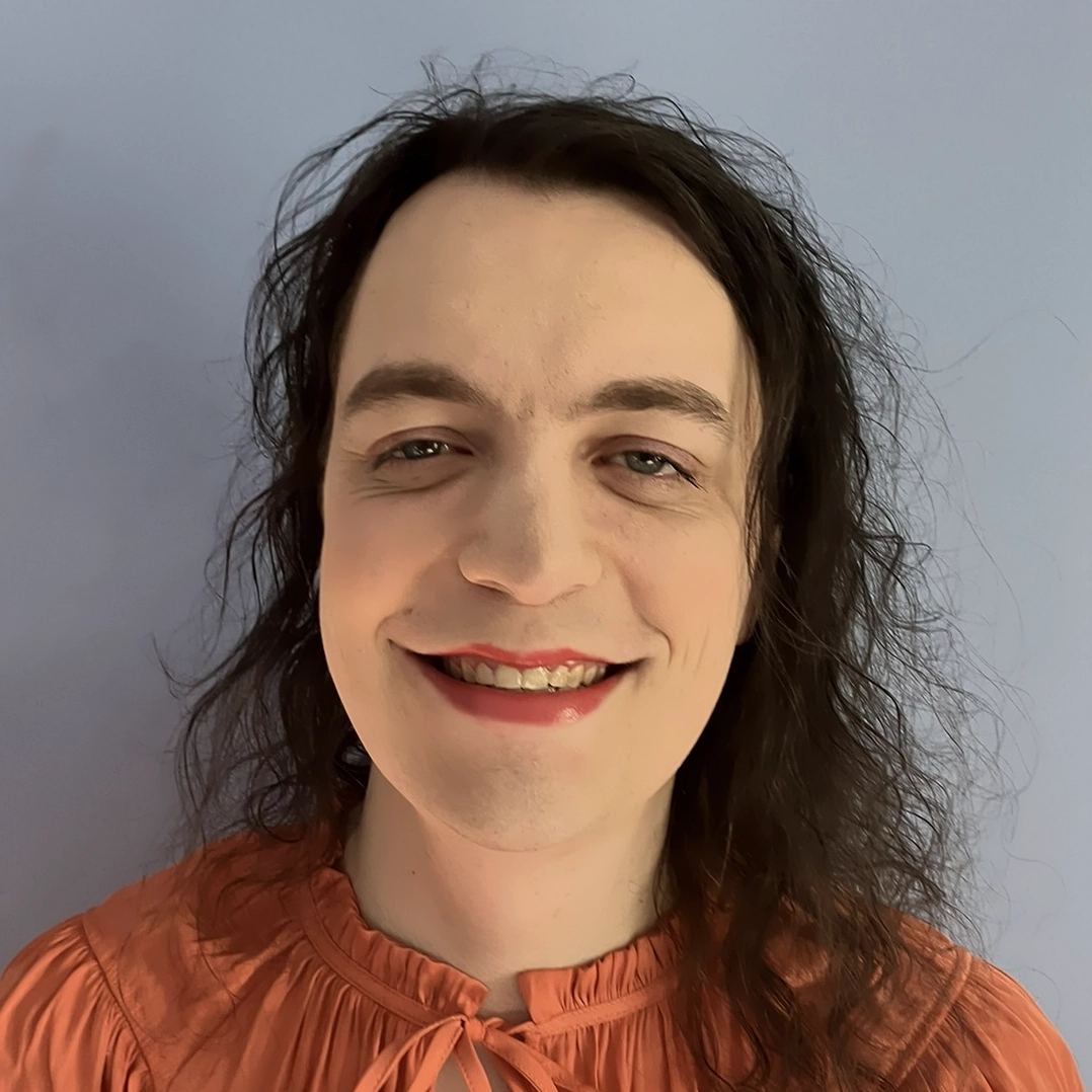 Wren's smiling face. She is a white woman with a round face. Her hair is long and dark brown.